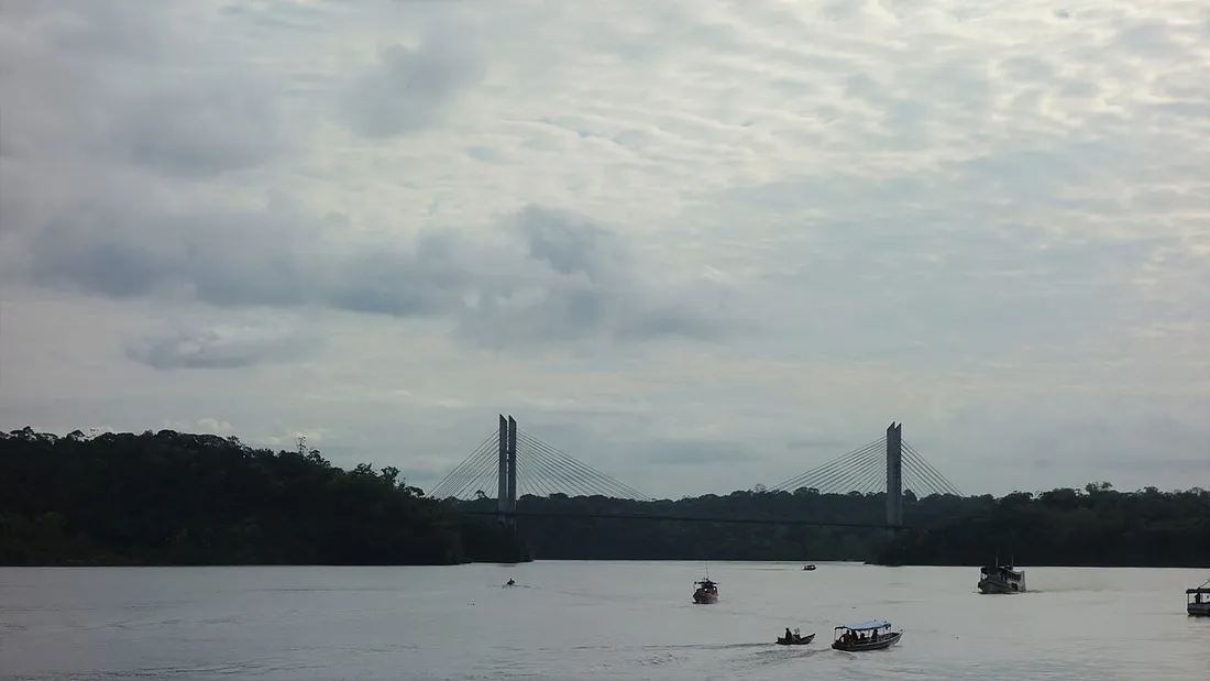 Le pont binational de l'Oyapock reliant Saint-Georges en Guyane a Oiapoque au Bresil, vu depuis le fleuve avec des pirogues et bateaux en circulation