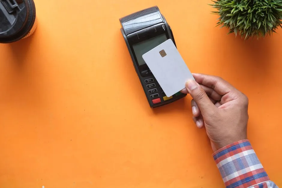 Main inserant une carte bancaire a puce dans un terminal de paiement, illustrant le reglement par carte et les frais bancaires