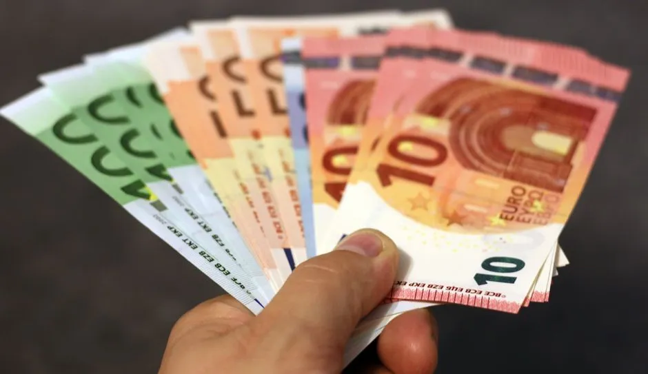 Main tenant un eventail de billets en euros (10, 20, 50 et 100 euros), la monnaie utilisee en Martinique pour les paiements en especes