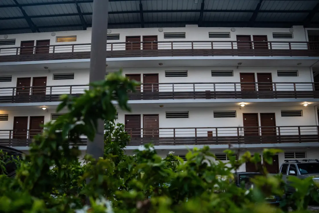 Façade de la résidence du Cocon Chic au crépuscule : coursives en bois sombre sur trois niveaux derrière la végétation