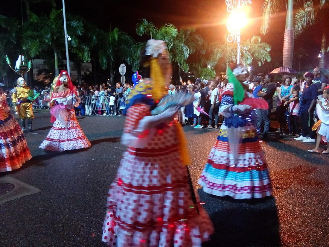 Groupe de Touloulous en robes à volants dansant lors d'un défilé nocturne du carnaval guyanais