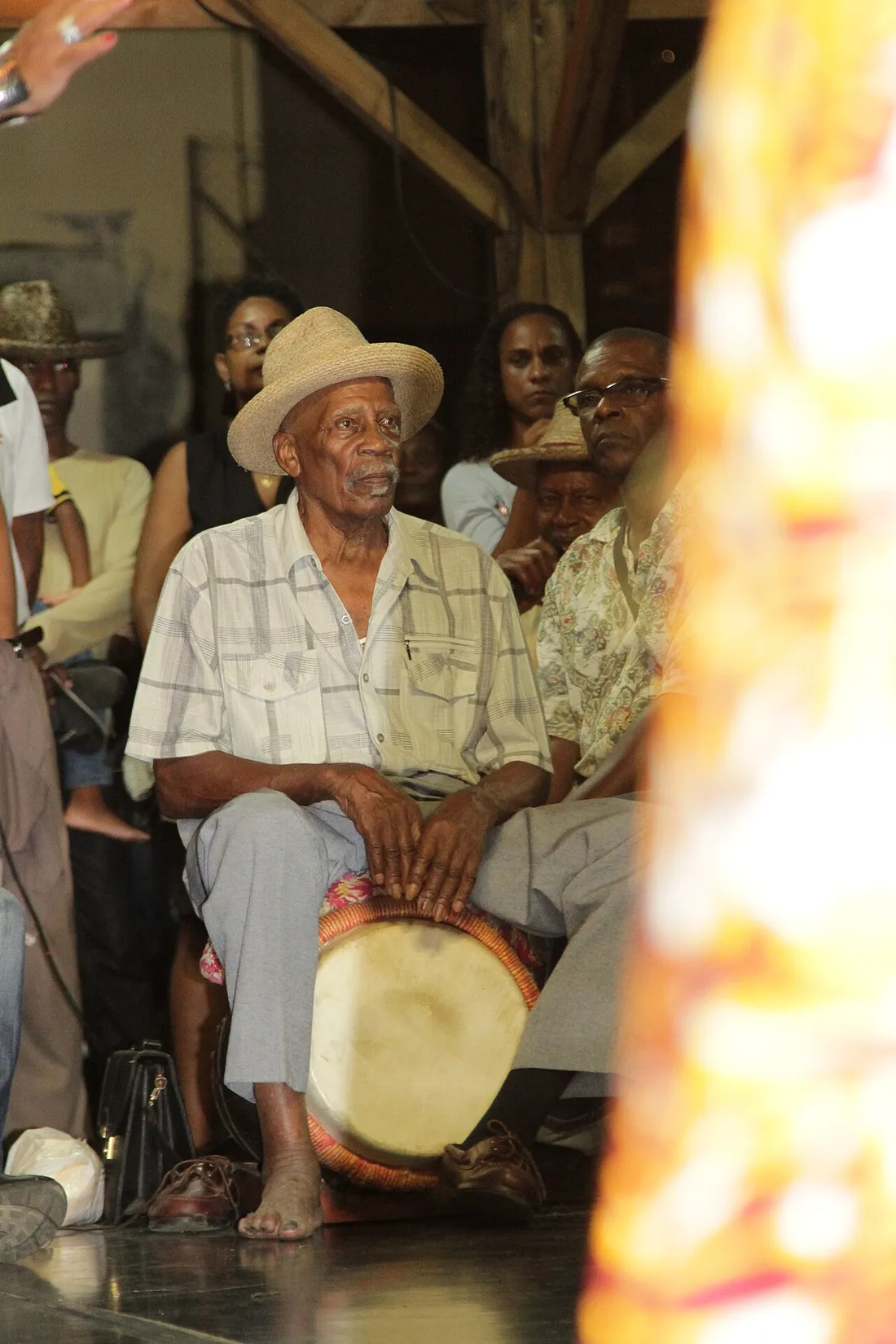 Musicien jouant du tambour bele (tanbou) assis lors d'une rencontre traditionnelle en Martinique