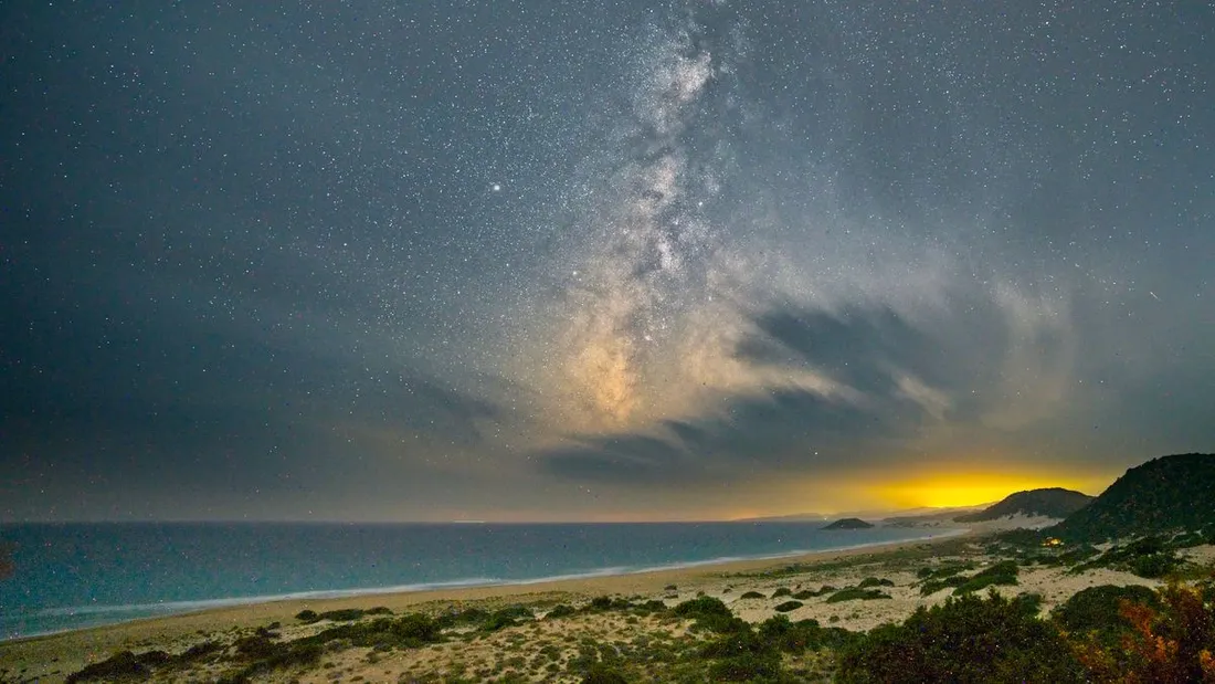 Plage tropicale deserte la nuit sous un ciel etoile et la Voie lactee au bord de la mer