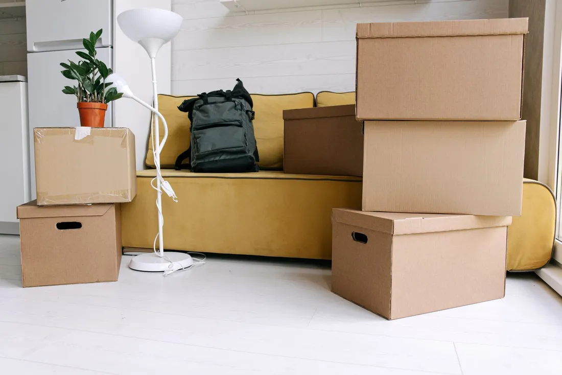 Cartons de déménagement empilés, sac à dos et lampe dans le salon d'un logement en cours d'emménagement