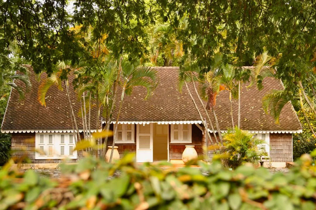 Bungalow tropical de style creole au toit de bardeaux, entoure de palmiers, typique d'une location individuelle aux Antilles