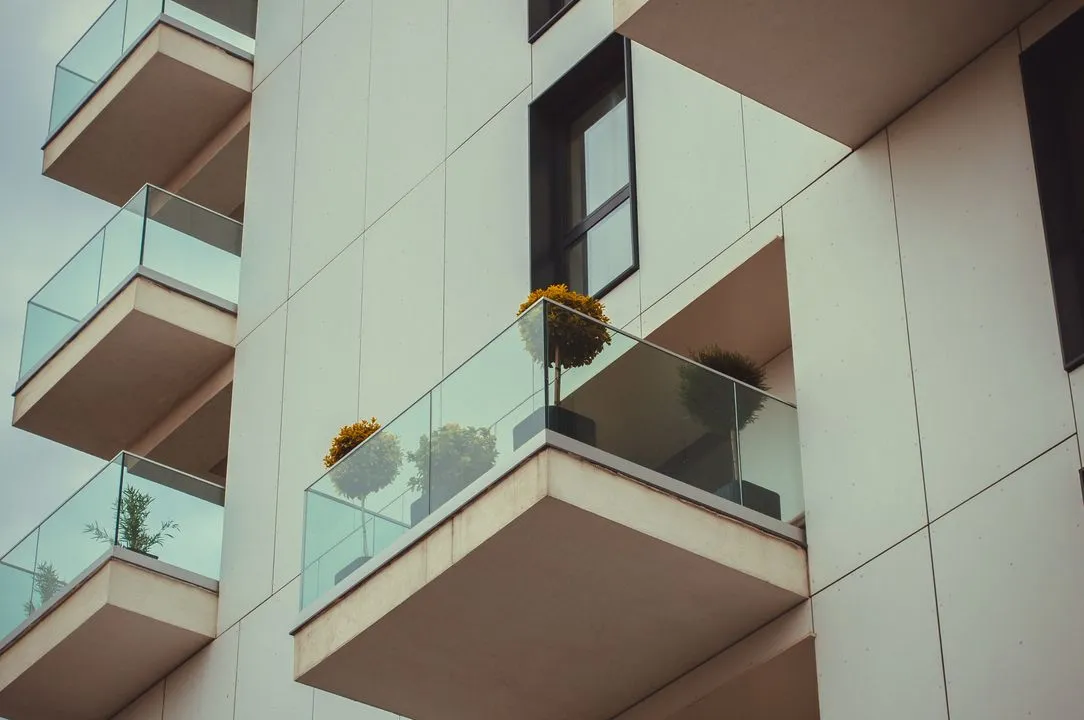 Facade d'un immeuble residentiel moderne avec balcons vitres et plantes, illustrant la location en appartement