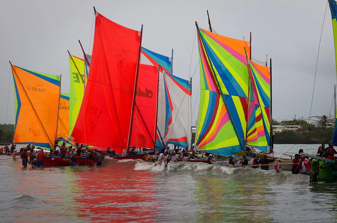 Yoles rondes aux voiles multicolores au départ d'une course du Tour des Yoles en Martinique