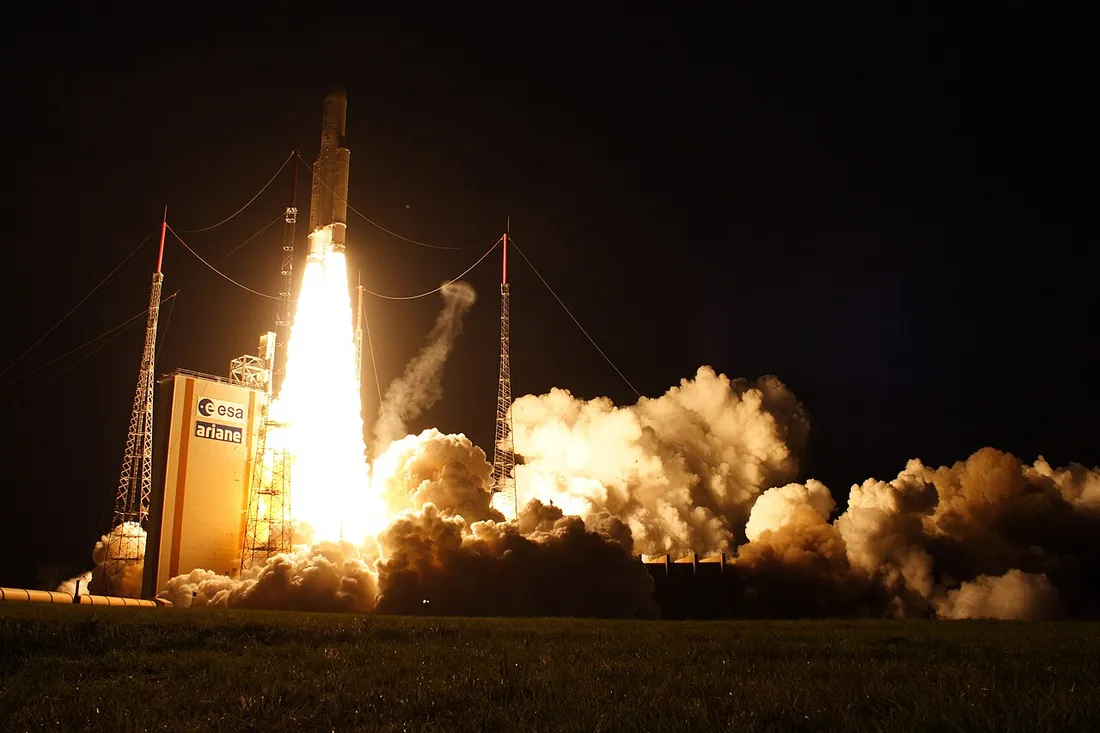 Decollage de nuit d'une fusee Ariane 5 depuis le pas de tir ELA-3 du Centre spatial guyanais a Kourou, flammes et panache de fumee illuminant la tour Ariane de l'ESA