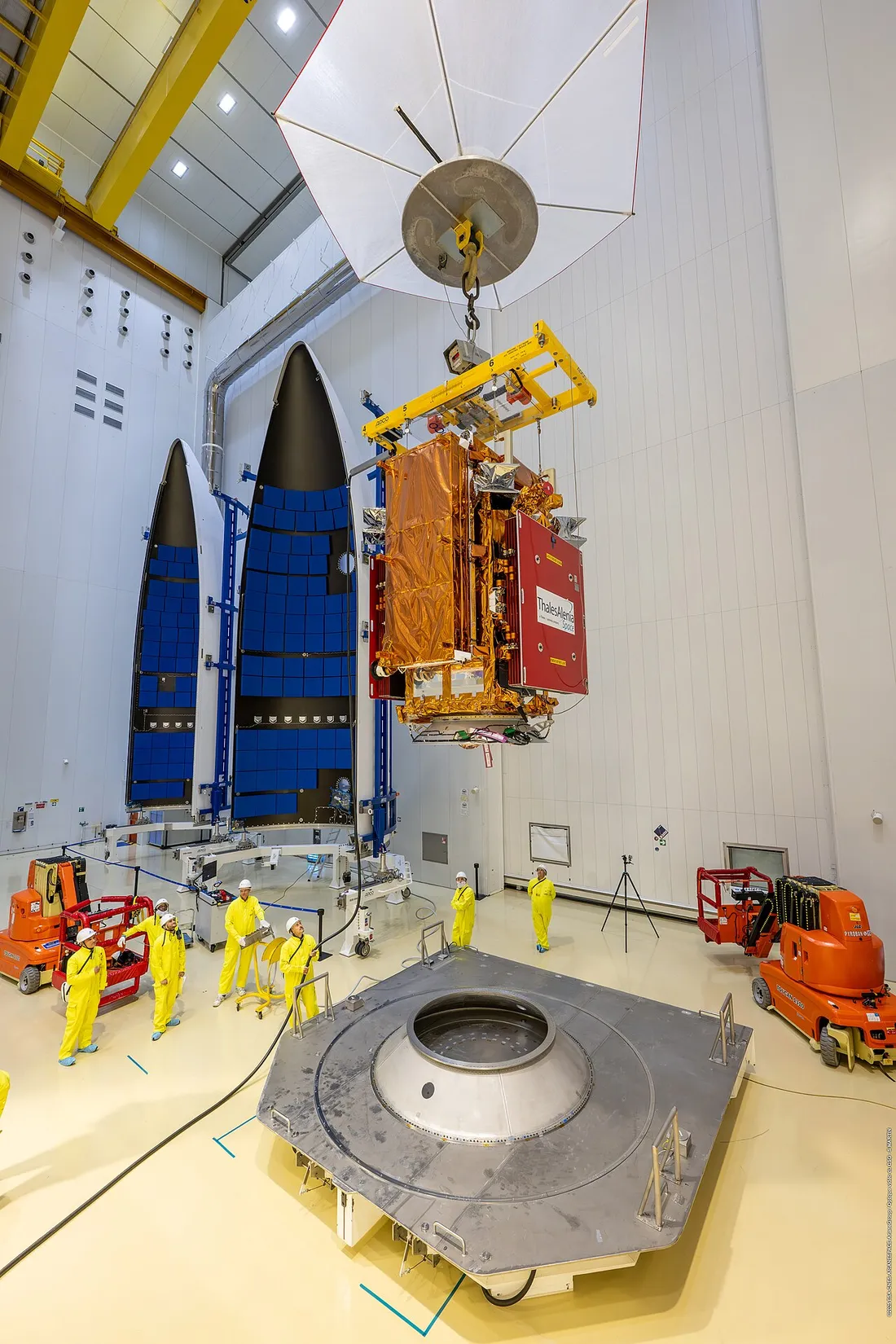 Integration d'un satellite Sentinel-1D abaisse sur l'adaptateur de lancement d'Ariane 6, avec les coiffes du lanceur en arriere-plan dans le batiment d'assemblage