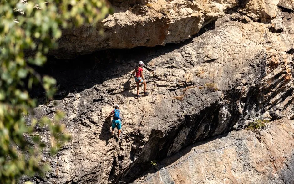 Deux grimpeurs progressant sur une paroi rocheuse équipée d'un câble de via ferrata