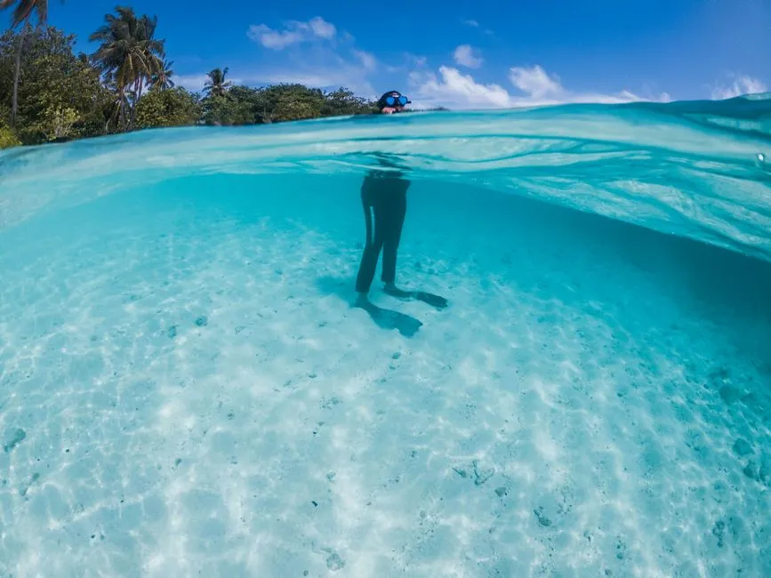 Personne masquee en train de faire du snorkeling dans une eau turquoise et limpide des Caraibes