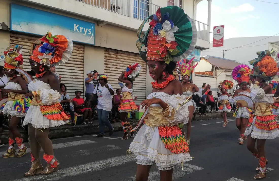 Defile du carnaval du Moule en Guadeloupe : danseuses en costumes a plumes colorees paradant dans les rues de la ville