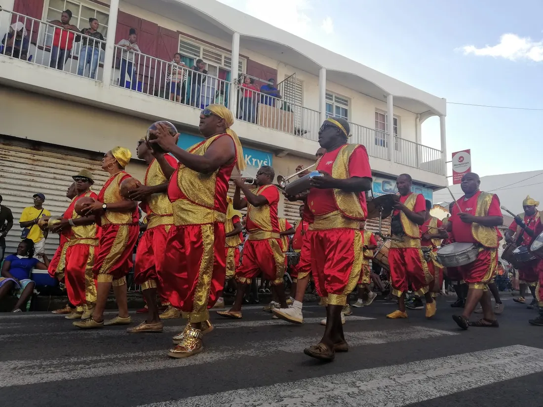Groupe de tambours et percussionnistes en tenues rouge et or paradant sur le parcours du carnaval du Moule en Guadeloupe