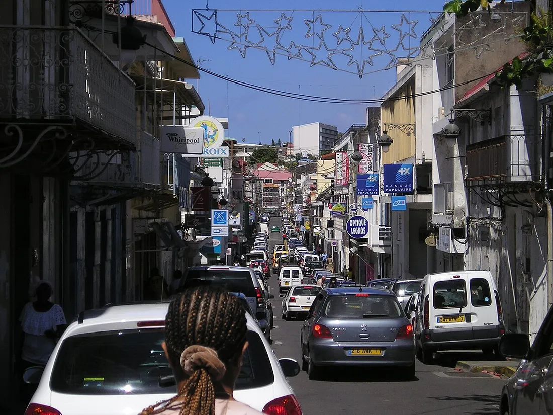 Rue commercante animee du centre-ville de Basse-Terre en Guadeloupe bordee de boutiques et de voitures