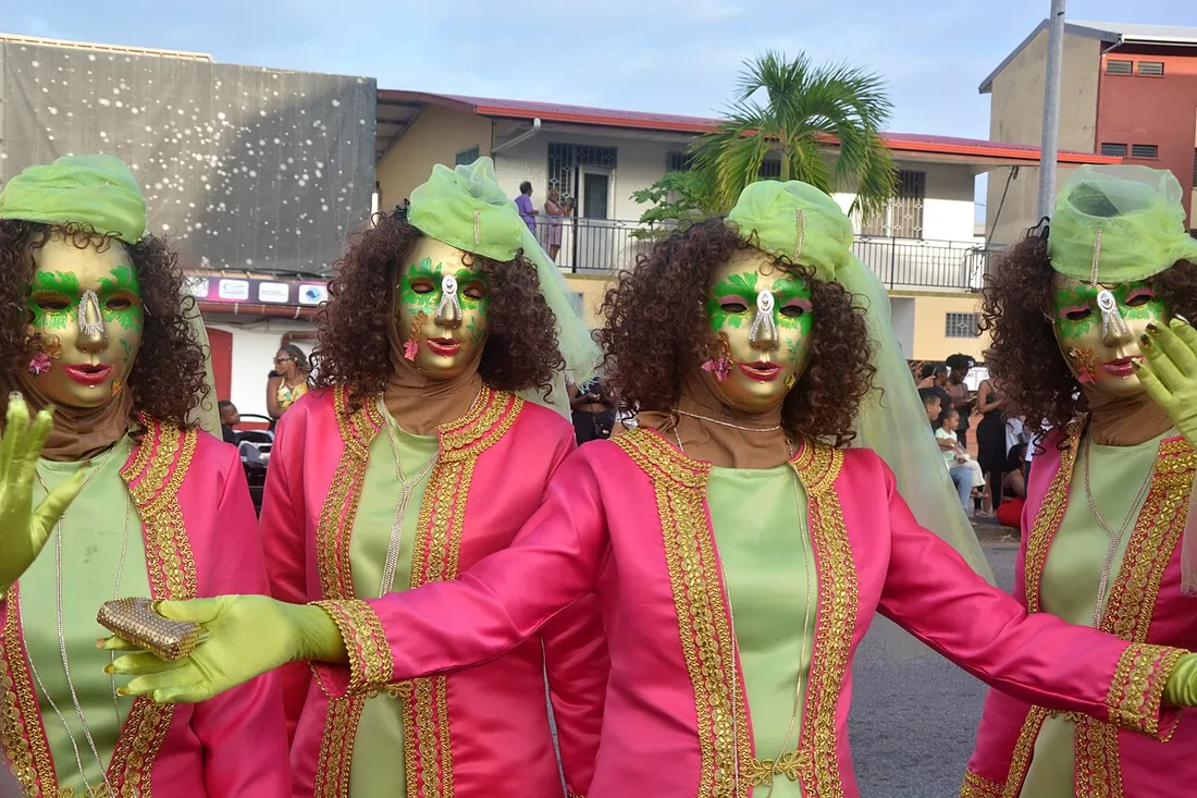 Touloulous masquées en costumes roses et verts brodés défilant au carnaval de Cayenne en Guyane en 2024