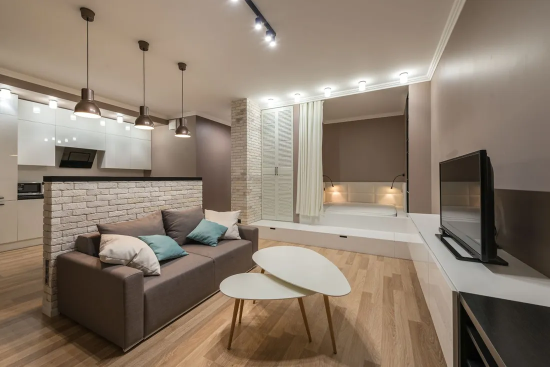 Intérieur d'un studio meublé moderne : coin salon avec canapé et table basse, cuisine ouverte et espace nuit, prêt à accueillir un occupant