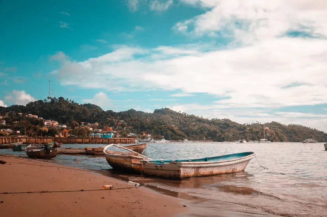 Barques de peche traditionnelles echouees sur une plage d'une baie caraibe, illustrant les zones de peche concernees par le chlordecone