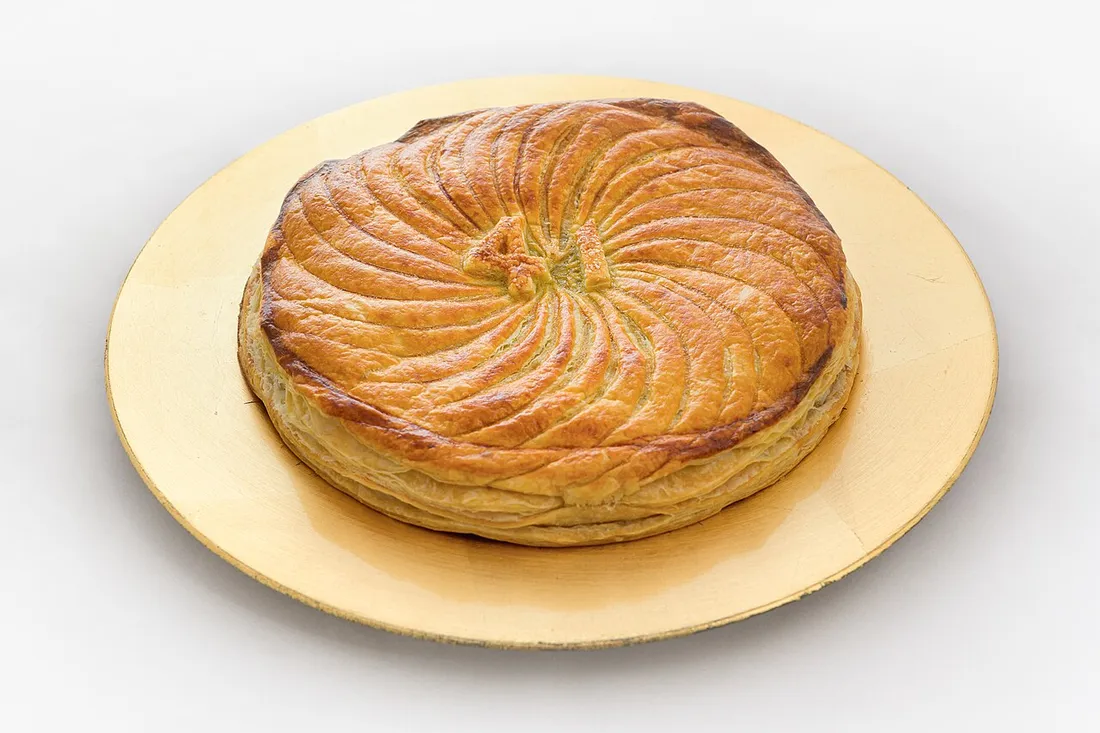 Galette des rois dorée à la frangipane posée sur une assiette, dessert des fêtes de fin d'année