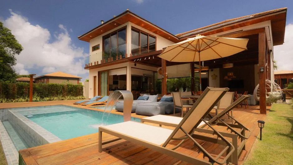 Villa tropicale haut de gamme avec piscine, terrasse en bois et transats, typique d'une location de vacances gérée par une conciergerie Airbnb