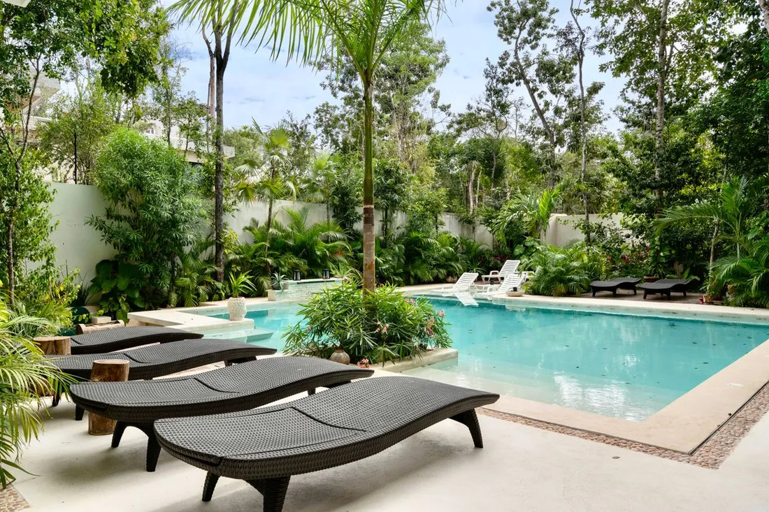 Piscine d'un hebergement de vacances avec transats et jardin tropical, illustrant les equipements d'un meuble de tourisme classe