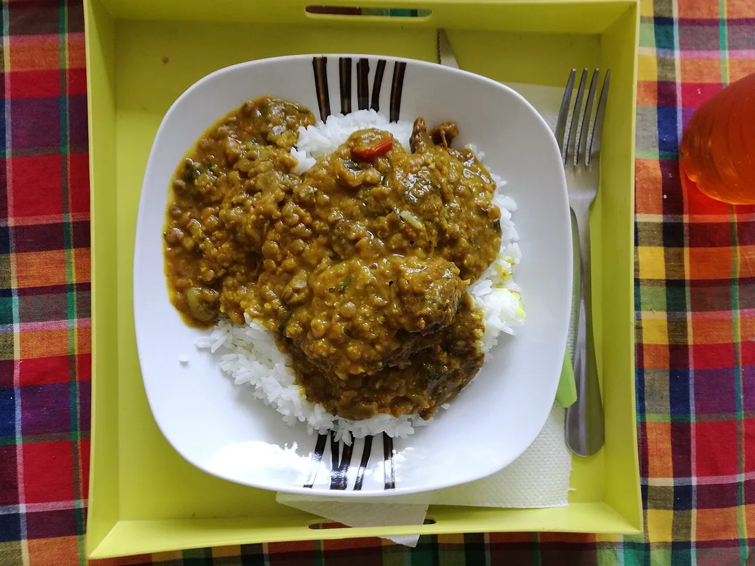 Colombo de viande nappe de sauce au curry servi sur du riz blanc, pose sur une nappe en madras antillais