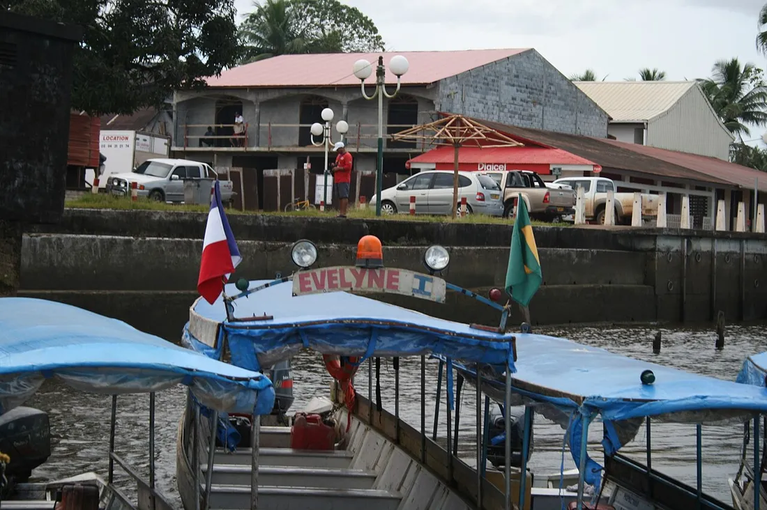 Pirogue de passagers transfrontalière arborant les drapeaux français et brésilien sur le fleuve Oyapock, devant le bourg de Saint-Georges-de-l'Oyapock