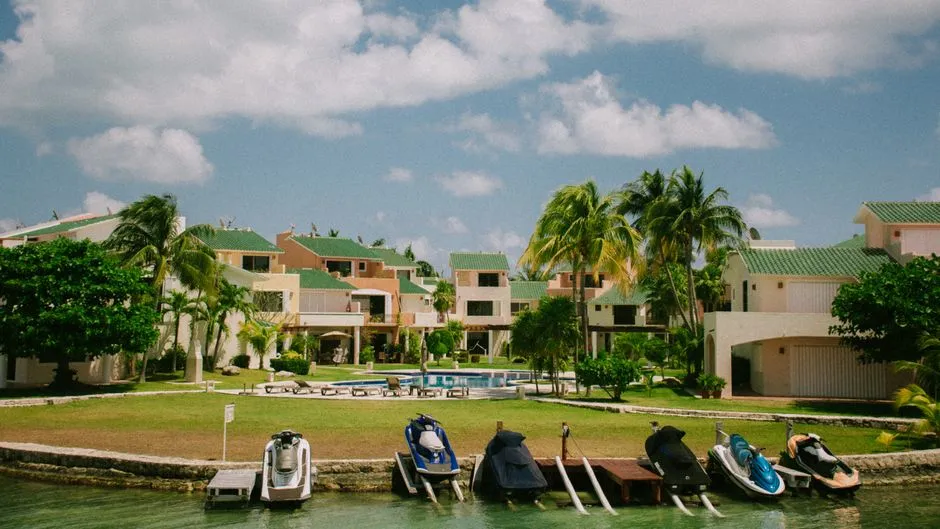 Villas de location de vacances tropicales avec piscine, pelouse et palmiers en bord d'eau