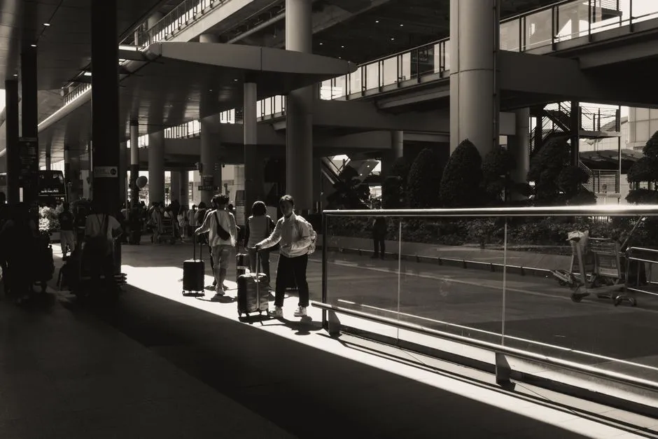 Voyageurs tirant leurs valises a roulettes dans le hall d'un terminal d'aeroport, clientele type captee par une conciergerie a proximite de l'aeroport