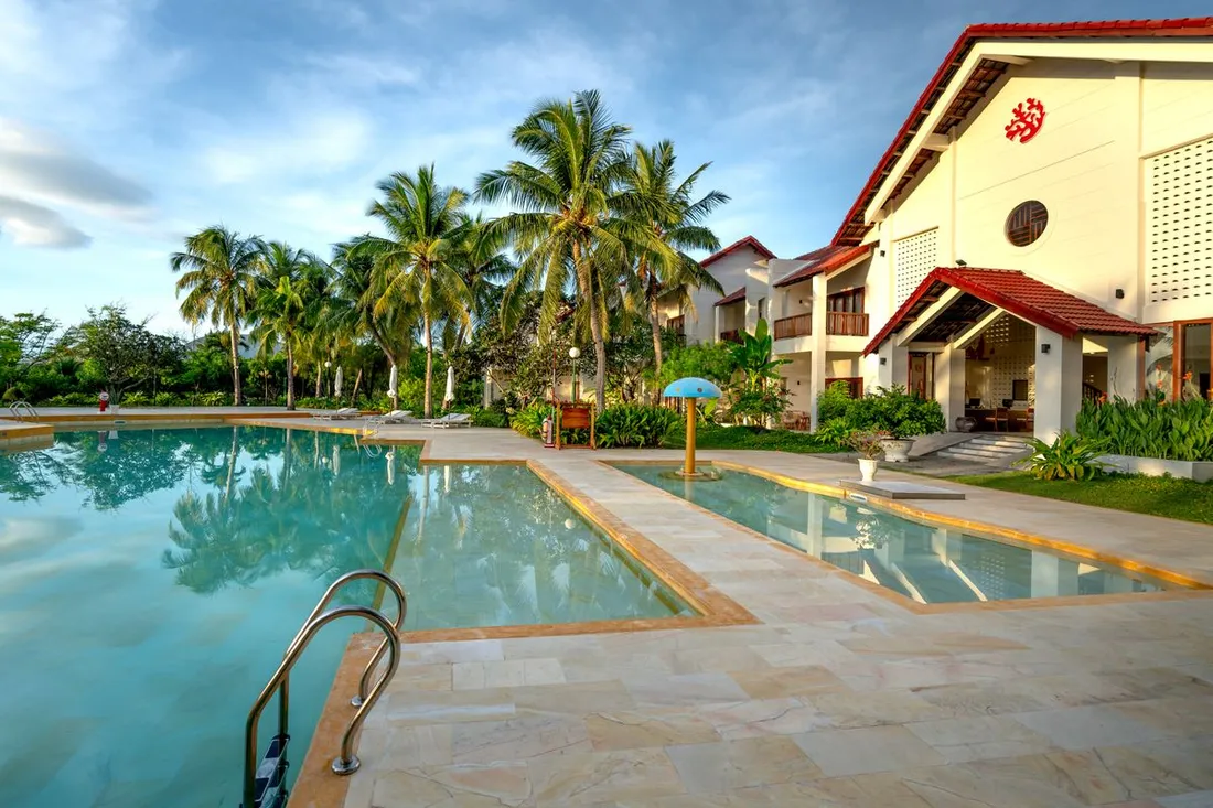 Villa tropicale de location avec piscine, terrasse carrelée et cocotiers, typique d'un bien géré en conciergerie Airbnb
