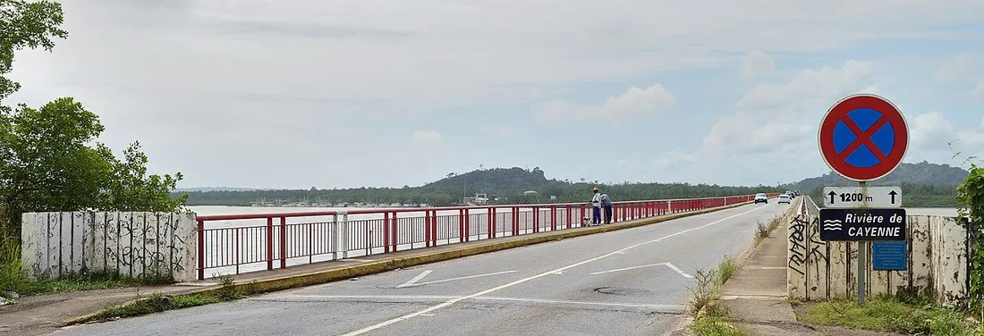 Route goudronnée franchissant le pont sur la rivière de Cayenne en Guyane, avec marquage au sol et panneau d'interdiction de stationner