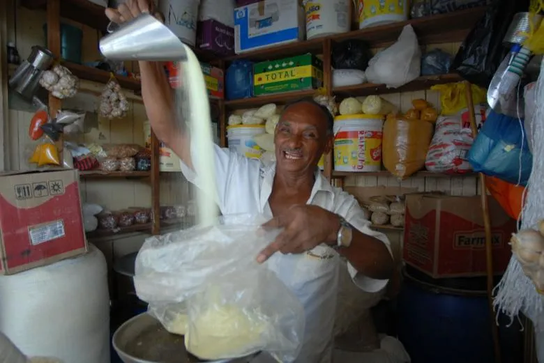 Vendeur versant du couac, la farine de manioc grillée jaune dorée, dans un commerce de produits locaux