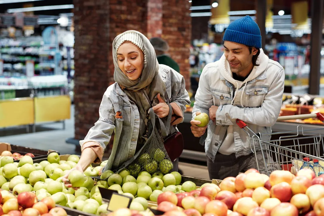 Un couple choisit des pommes et des legumes frais dans les rayons d'un supermarche