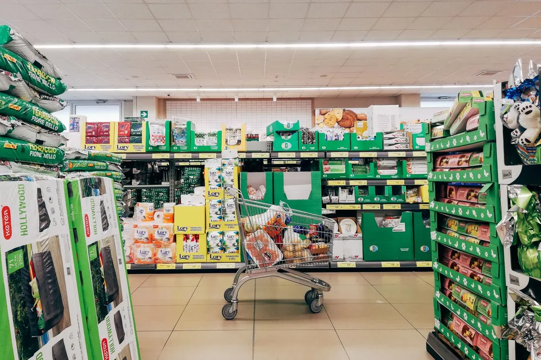 Un chariot rempli de provisions au milieu d'une allee de supermarche