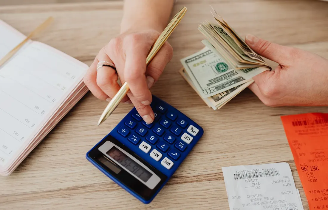 Mains comptant de l'argent liquide avec une calculatrice, un agenda et des tickets de caisse