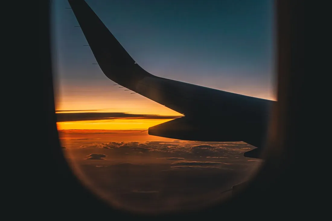 Aile d'avion vue depuis un hublot au coucher du soleil pendant le long vol entre la France et la Guadeloupe