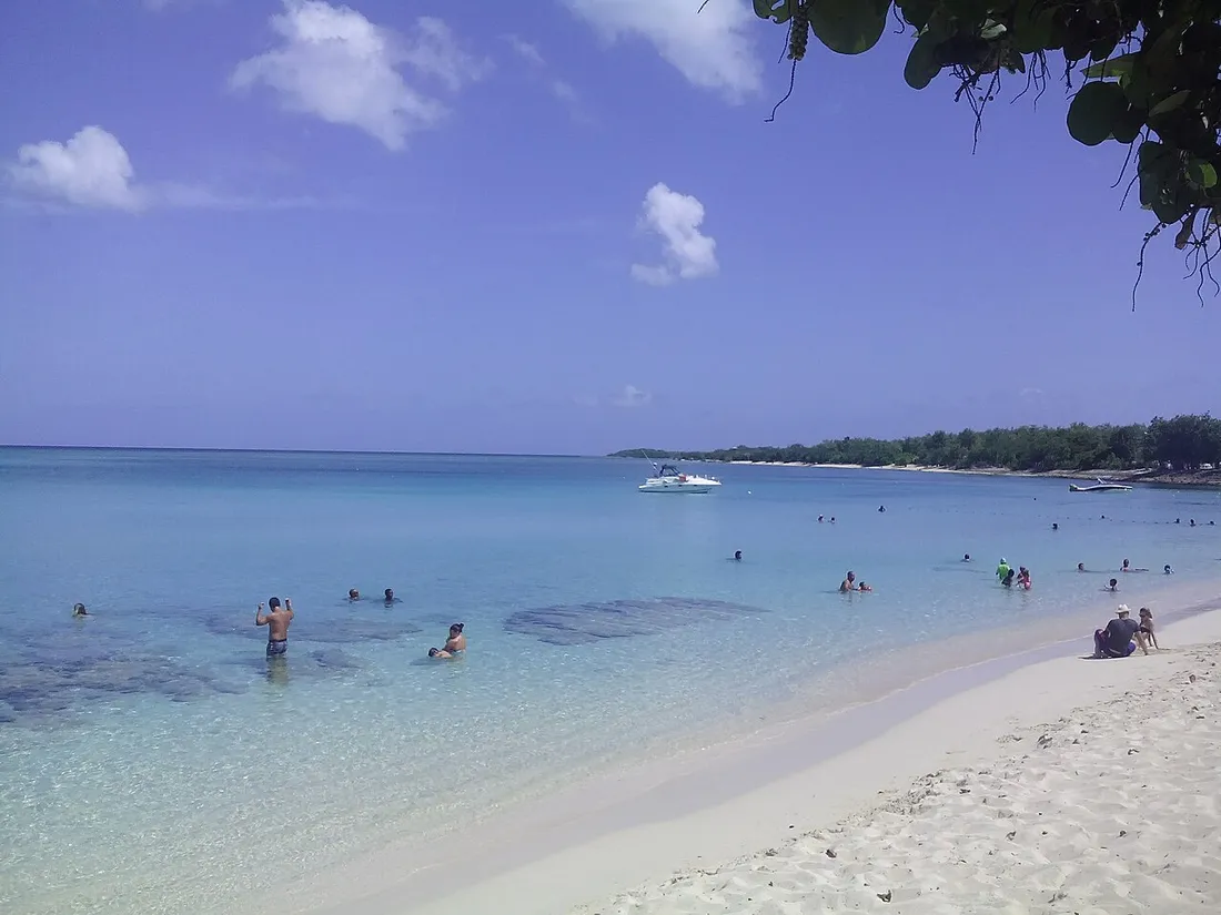 Plage de sable blanc et eau turquoise à Port-Louis en Guadeloupe sous un ciel ensoleillé