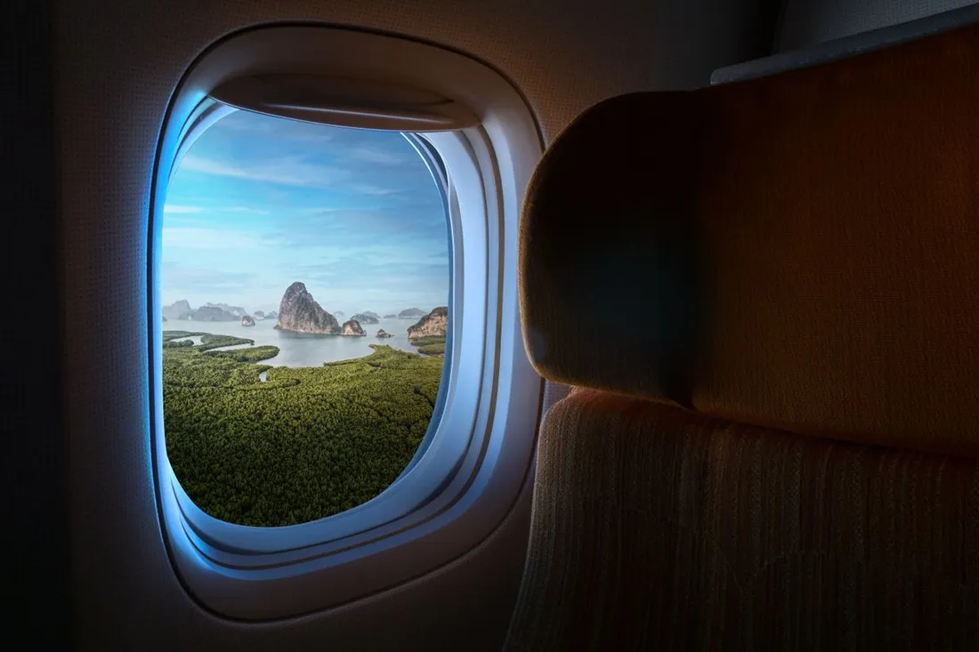 Vue depuis le hublot d'un avion sur un paysage insulaire tropical pendant la descente, illustrant l'arrivee apres un long vol vers la Martinique