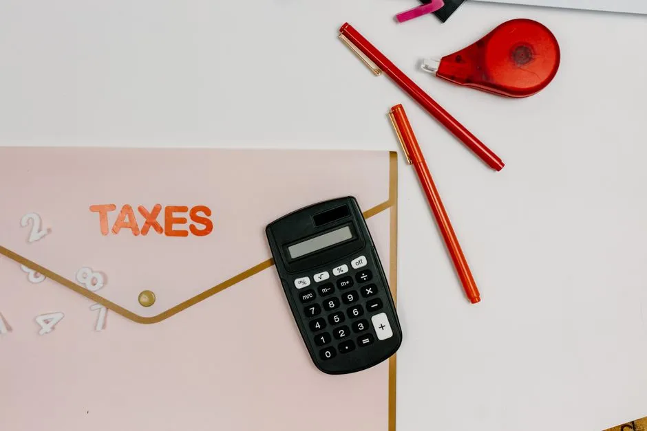 Calculatrice posée sur une enveloppe étiquetée TAXES avec des stylos, illustrant le calcul de la réduction d'impôt liée à la loi Girardin