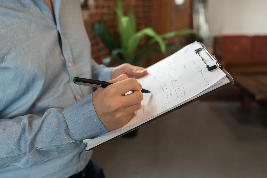 Une personne remplit une checklist au stylo sur un porte-bloc