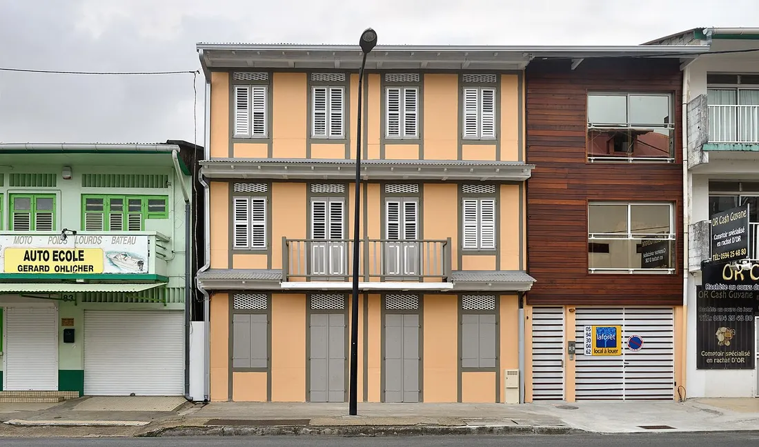 Maison creole renovee a Cayenne portant une pancarte local a louer, entouree de commerces de proximite