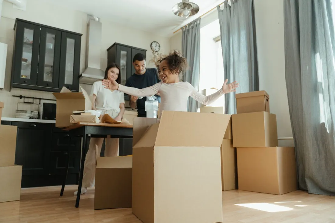 Famille joyeuse en train de déballer des cartons de déménagement dans la cuisine de son nouveau logement