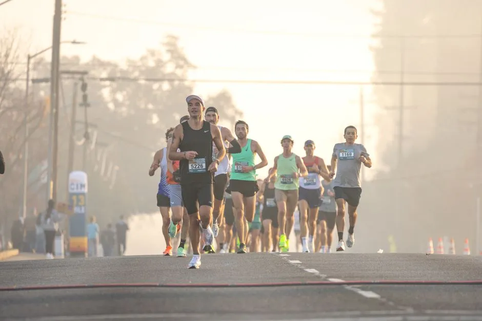 Peloton de coureurs dossards au petit matin sur une route, ambiance d'une course sur route de type demi-marathon