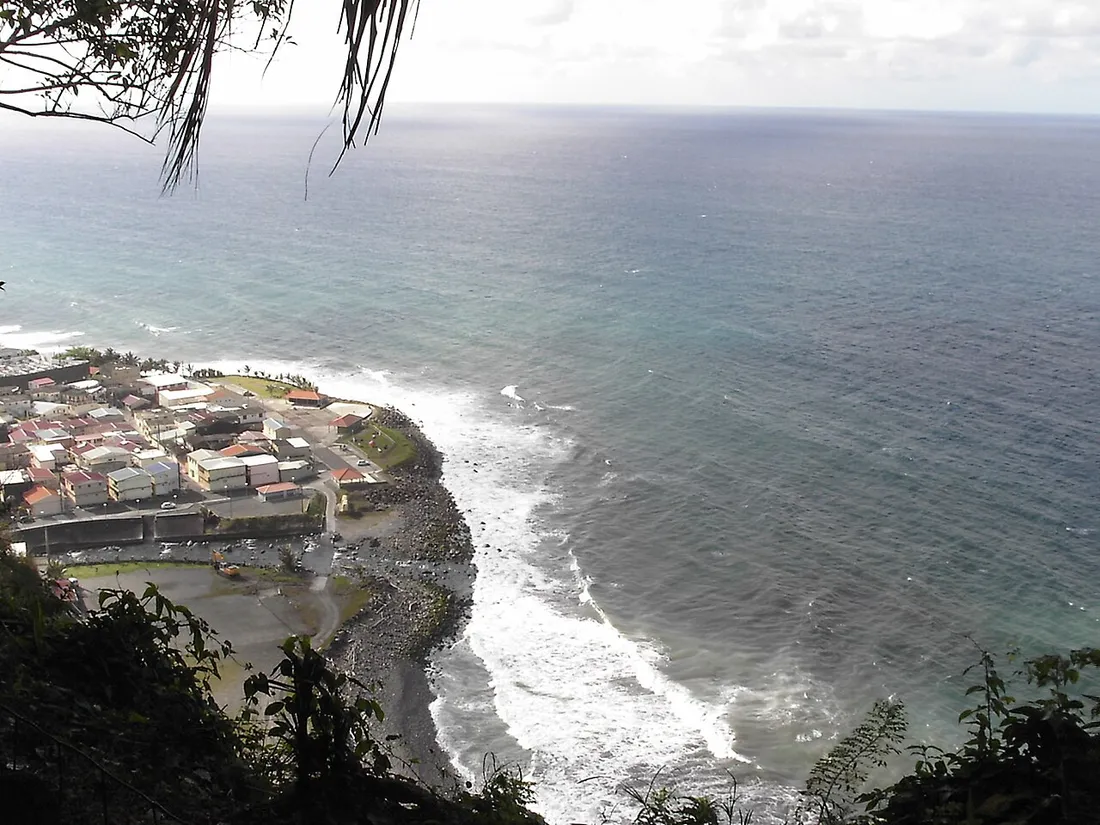 Vue plongeante sur la cote sauvage et rocheuse du grand Nord de la Martinique a Grand-Riviere, avec le village au bord de l'ocean Atlantique et les vagues sur le rivage