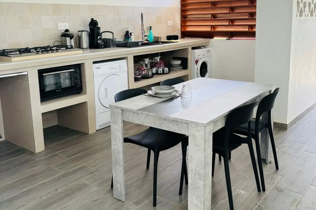 Cuisine de la maison Tropikana à Rémire-Montjoly : plaques de cuisson, four, lave-linge et table pour quatre