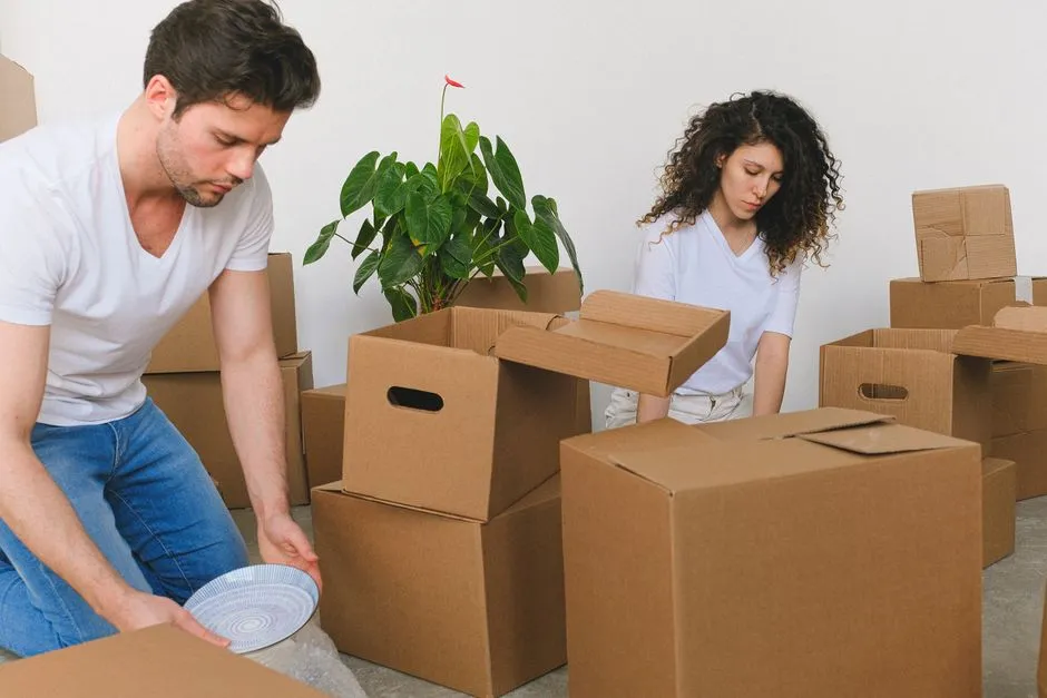 Un couple emballe ensemble de la vaisselle dans des cartons de déménagement avant son départ en mutation