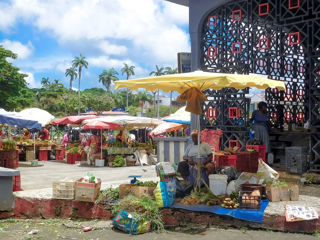 Marché en plein air de Pointe-à-Pitre en Guadeloupe, avec étals de fruits, parasols et marchands où les touristes doivent rester vigilants sur les prix