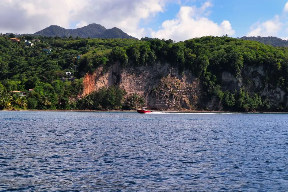 Bateau rapide longeant la côte verdoyante et les falaises de Sainte-Lucie, ambiance d'excursion maritime au départ de la Martinique