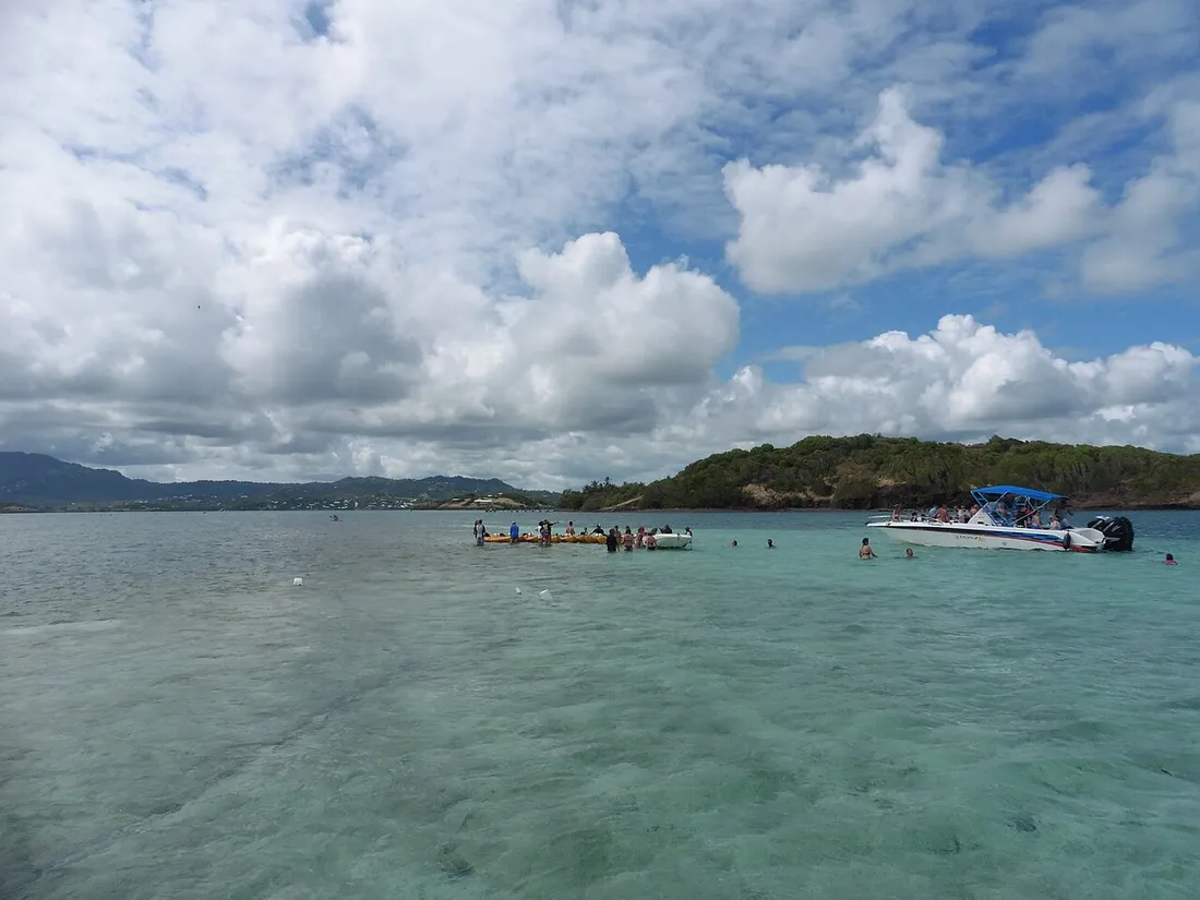 Excursionnistes debout dans les eaux turquoise peu profondes de la Baignoire de Joséphine, dans la baie du François en Martinique, avec bateau d'excursion et kayaks près des îlets