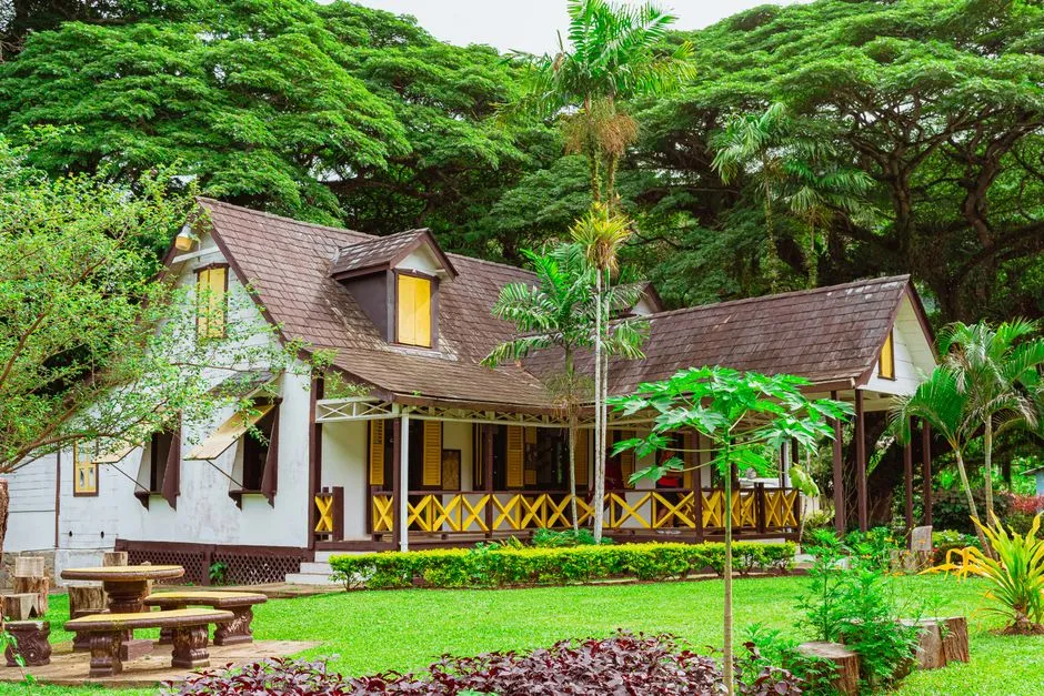 Gîte créole traditionnel en bois avec véranda à colombages, entouré d'un jardin tropical, typique d'un meublé de tourisme aux Antilles