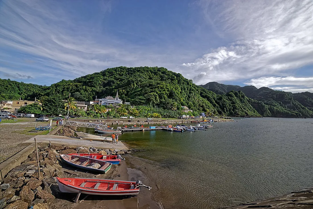 Le village de pêcheurs de Grand-Rivière en Martinique, ses yoles colorées échouées sur la plage de galets et le ponton devant les collines verdoyantes